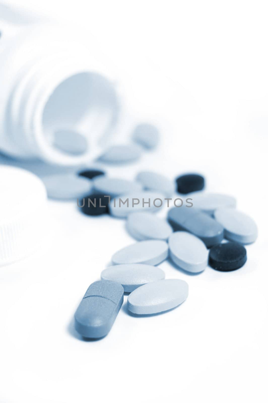 some colourful pills with bottle in blue tones