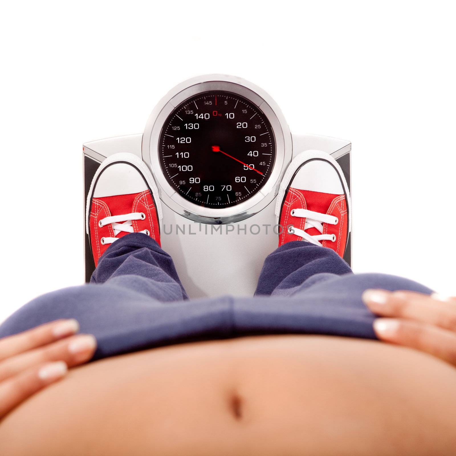 Athletic young girl measuring her weight on a balance