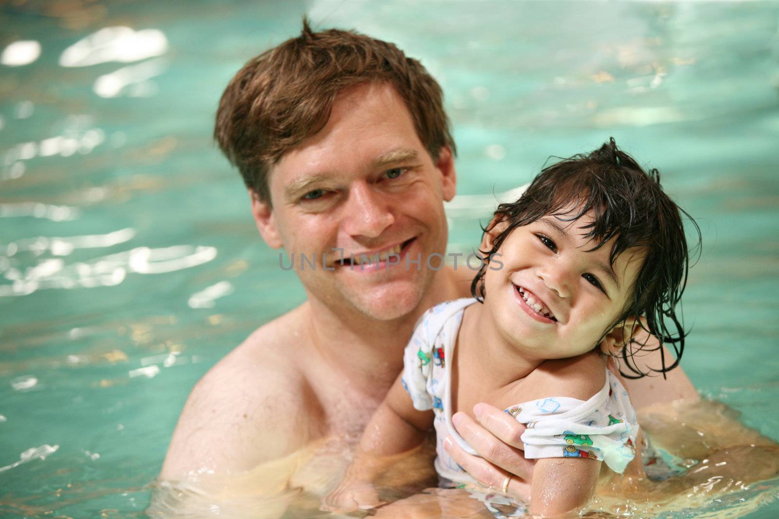Father and toddler boy swimming in pool