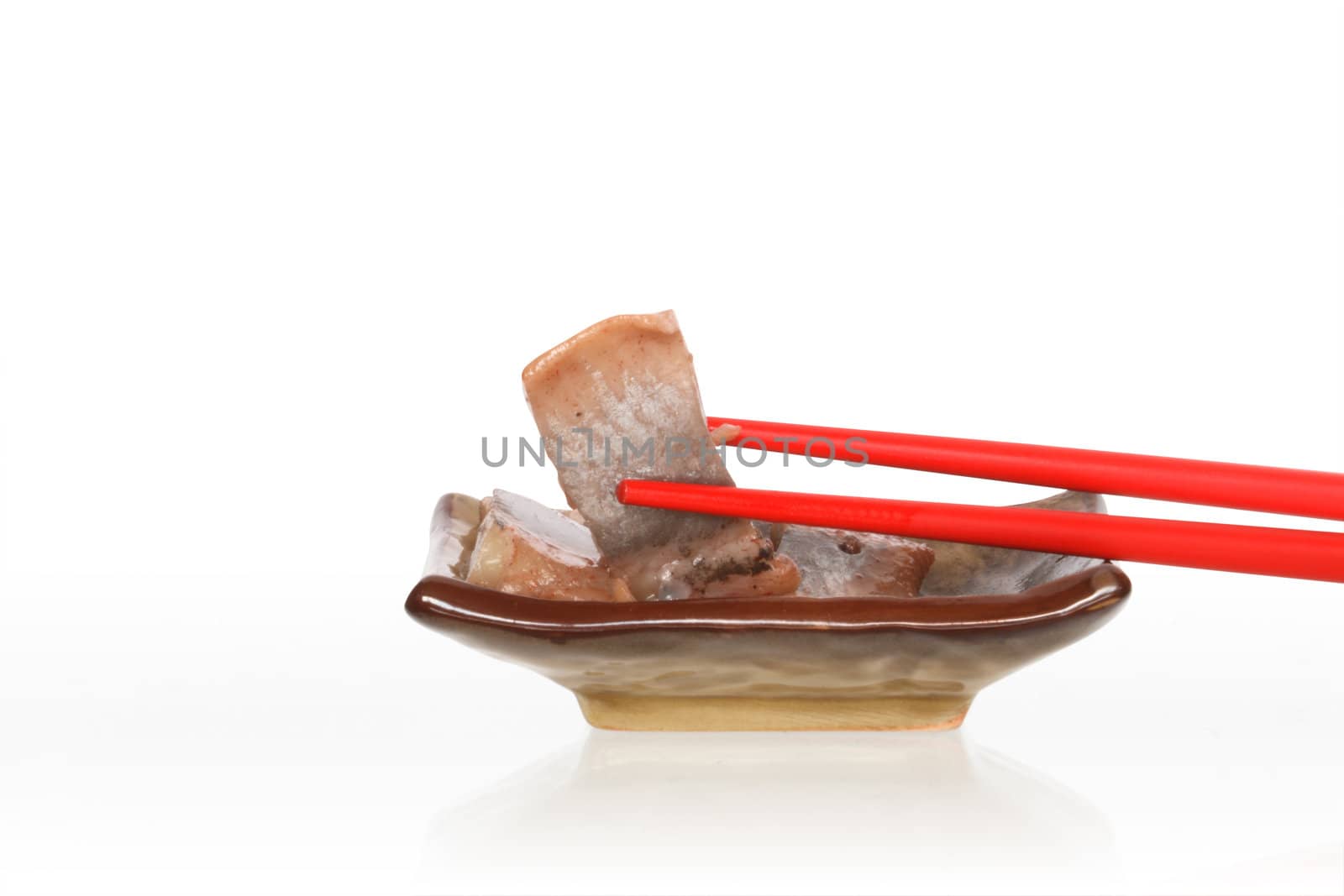 Pair of red chopsticks lying on plate with fish. Isolated on white with clipping path