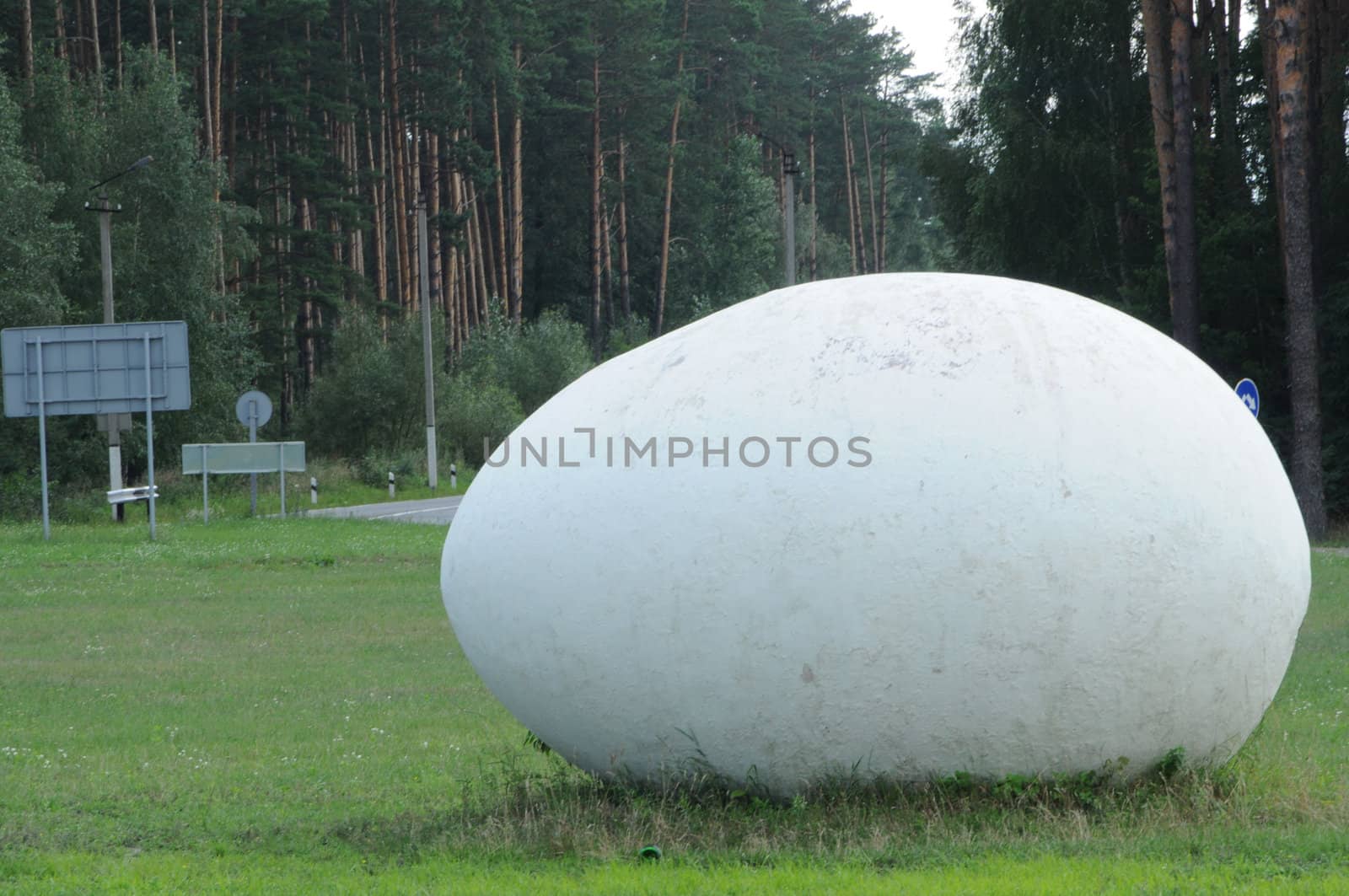 giant stone egg on a lawn not far from a road