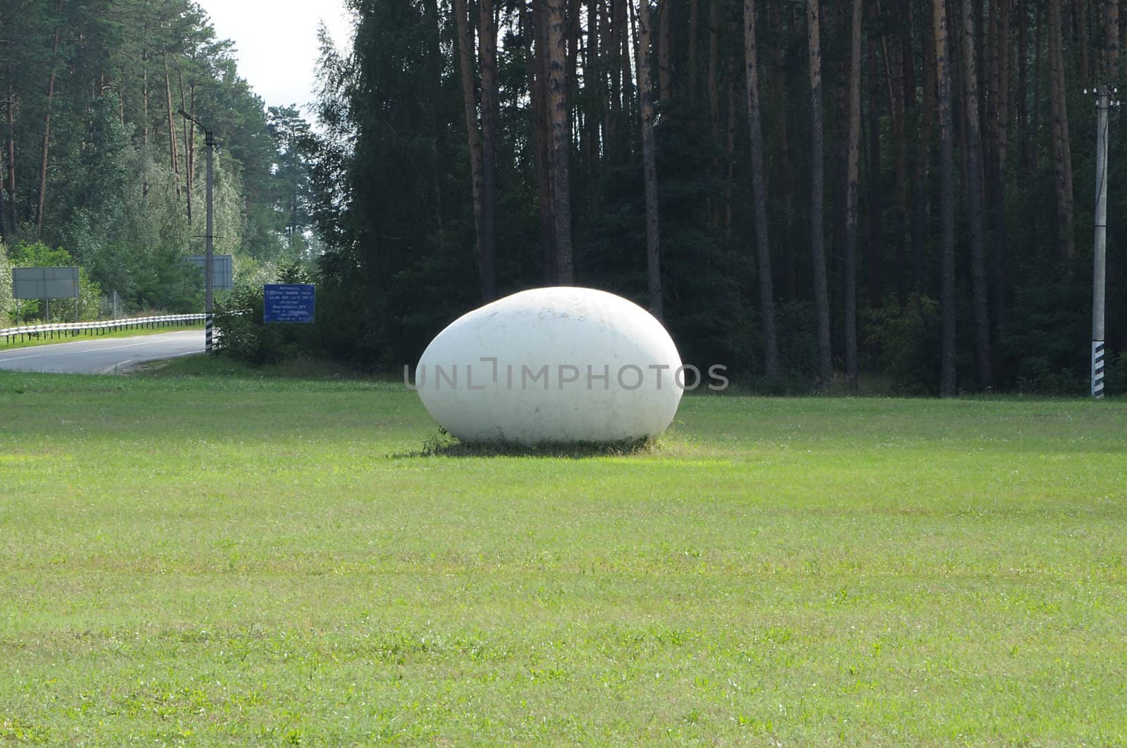 giant stone egg on a lawn not far from a road