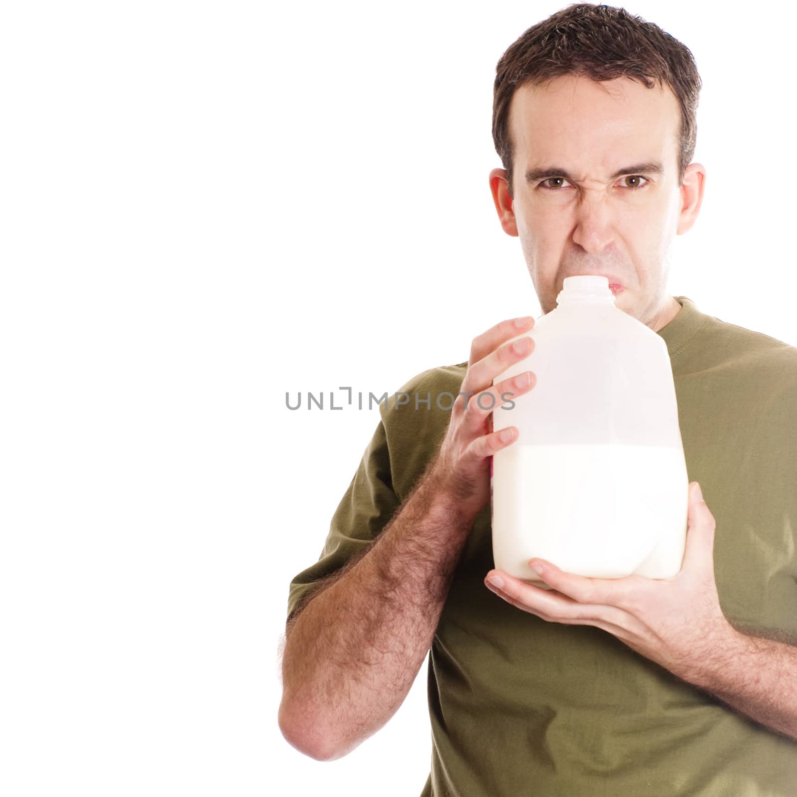 A young man smelling a container of spoiled milk, isolated against a white background