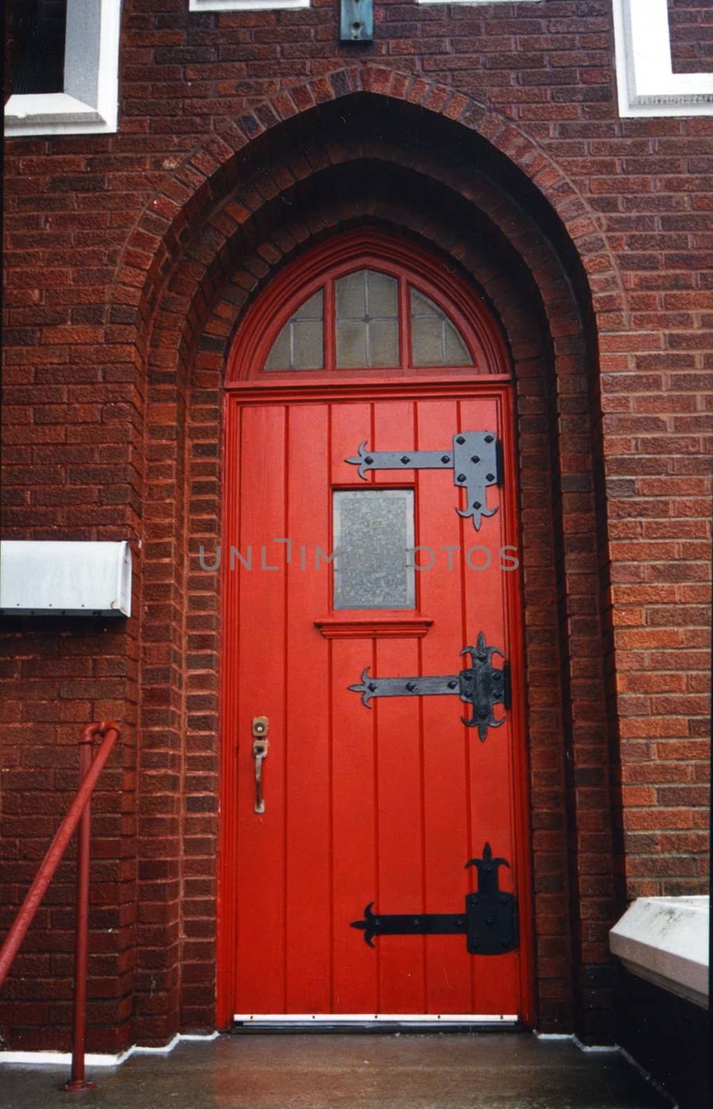 Red arched door on brick church