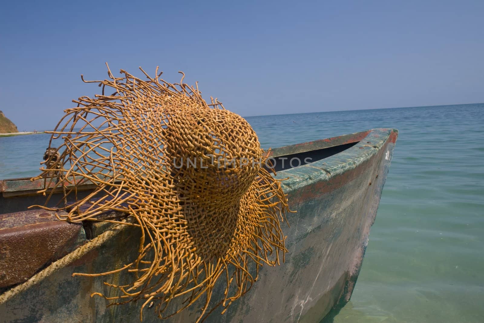 Serene scene with old fishing boat and large straw hat hanging from cleat