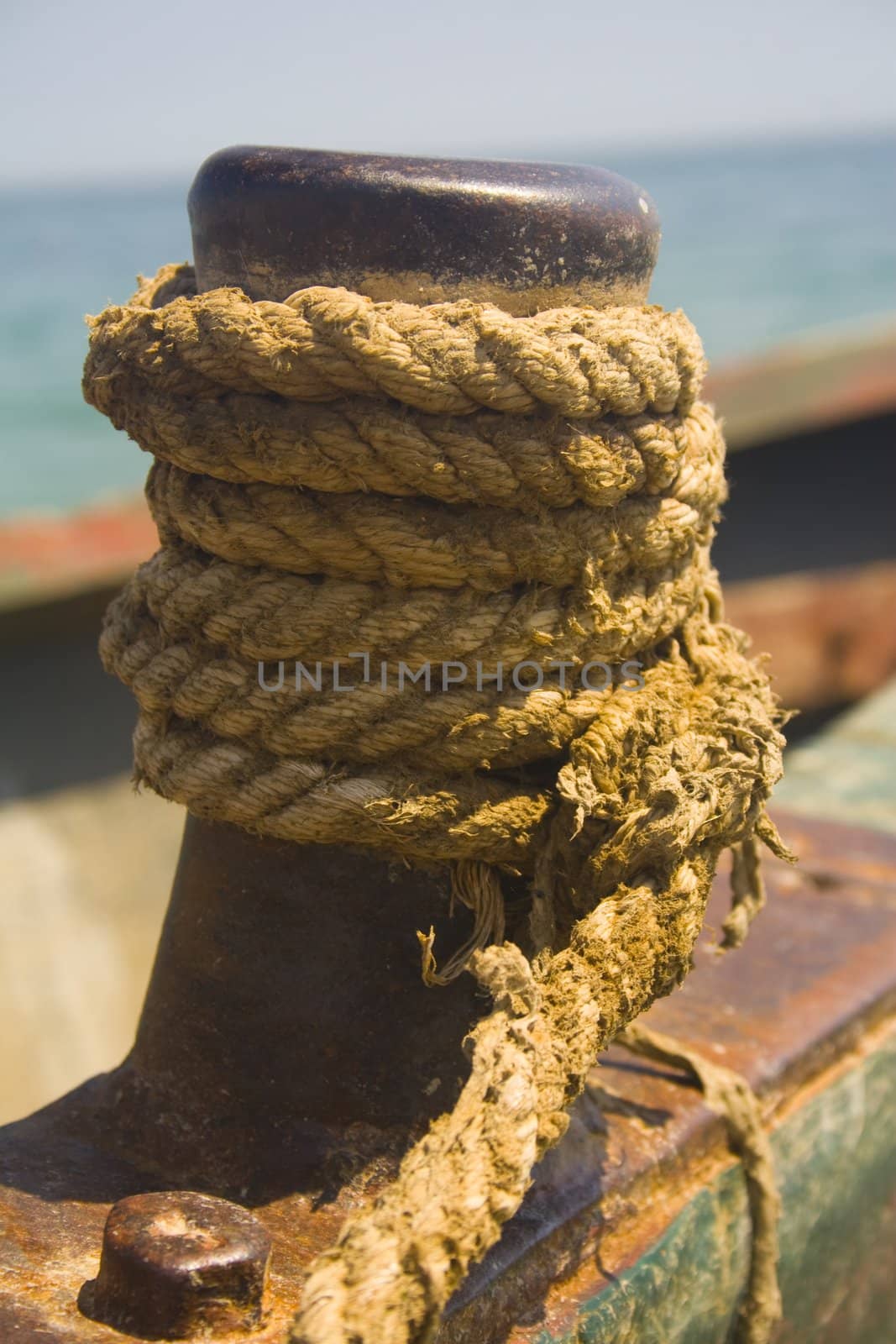Close-up of rope wrapped around rusty fishing boat cleat