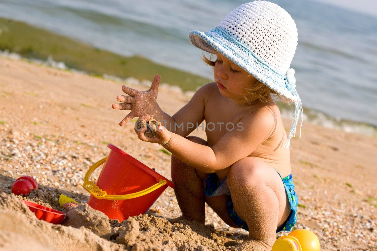 little girl in the bonnet plaing with sand, childhood