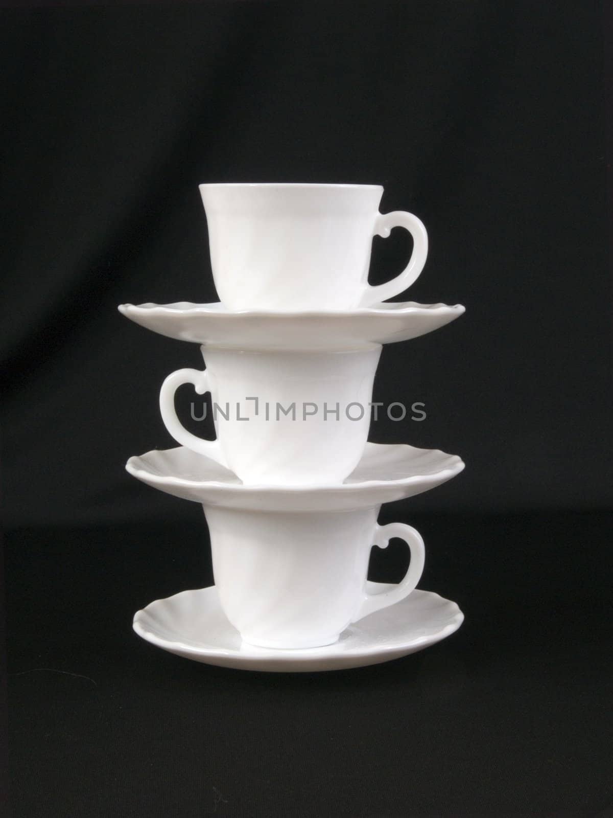 A stack of cups and saucers on the black background