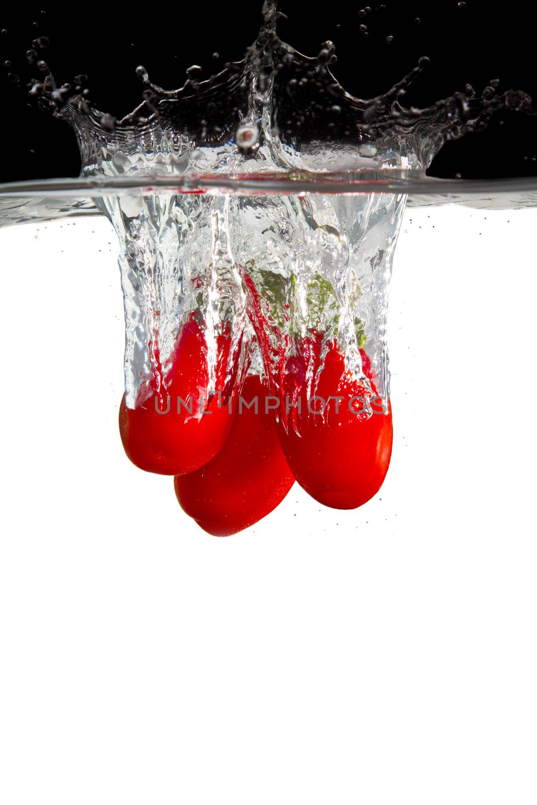 some red tomatos thrown in water with black and white background