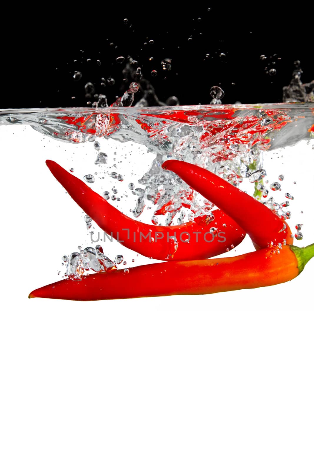 three red chillis thrown in water with black and white background