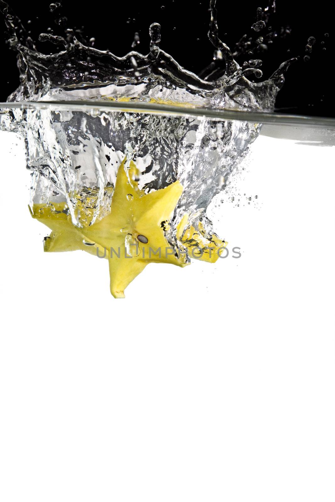 some yellow carambolas thrown in water with black and white background