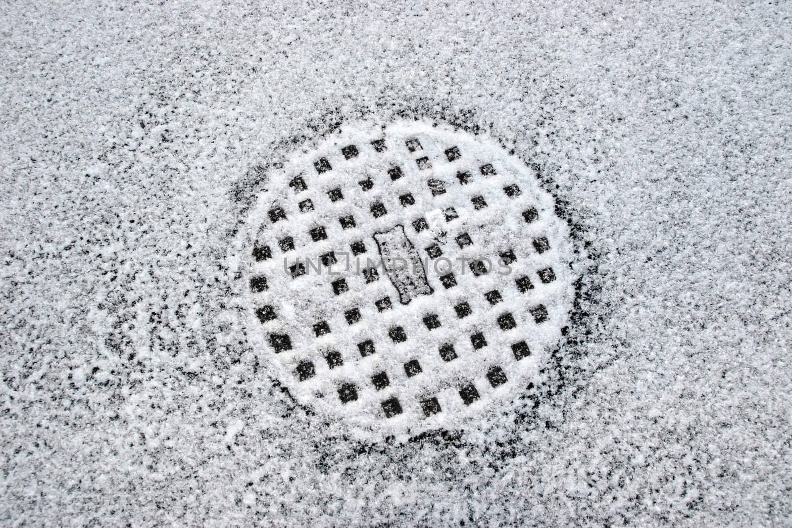 a snow covered manhole cover on the road surface