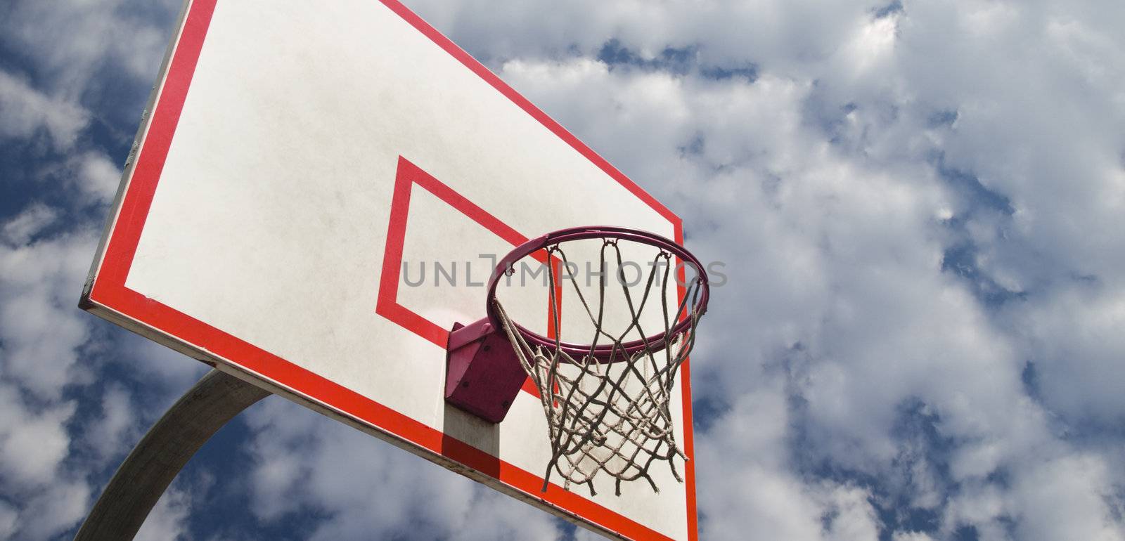 A basketball ring over a blue sky with clouds.