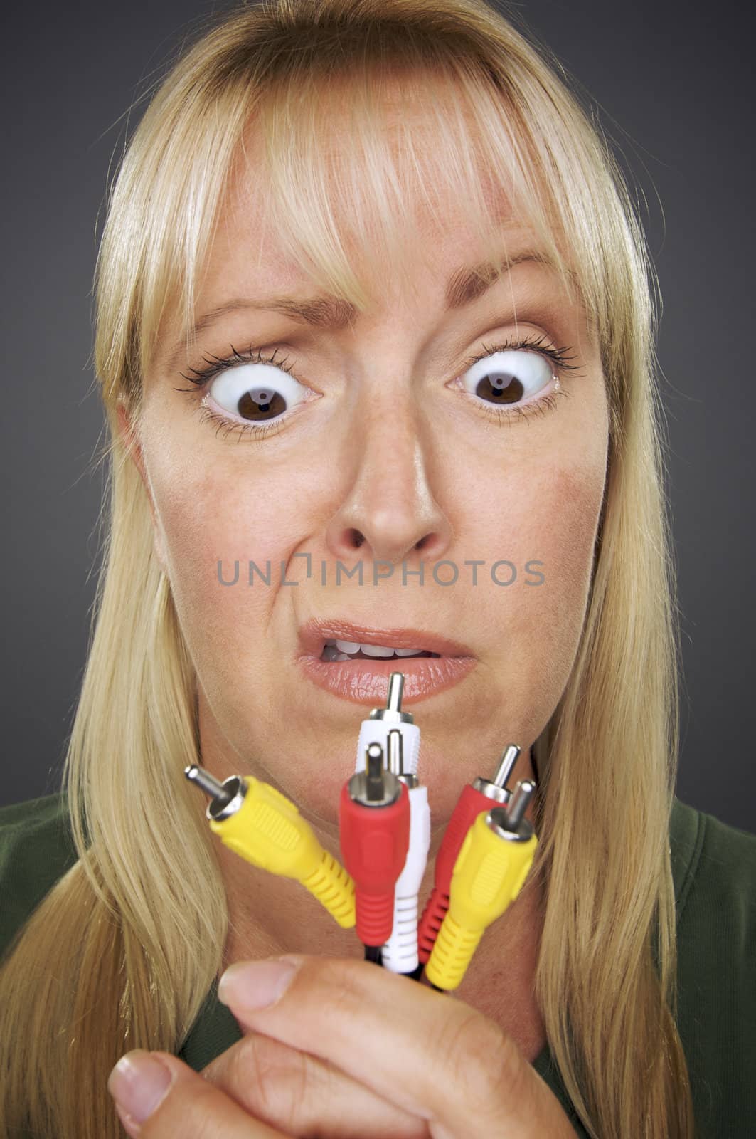 Confused Woman Holding Electronic Cables Against a Grey Background.