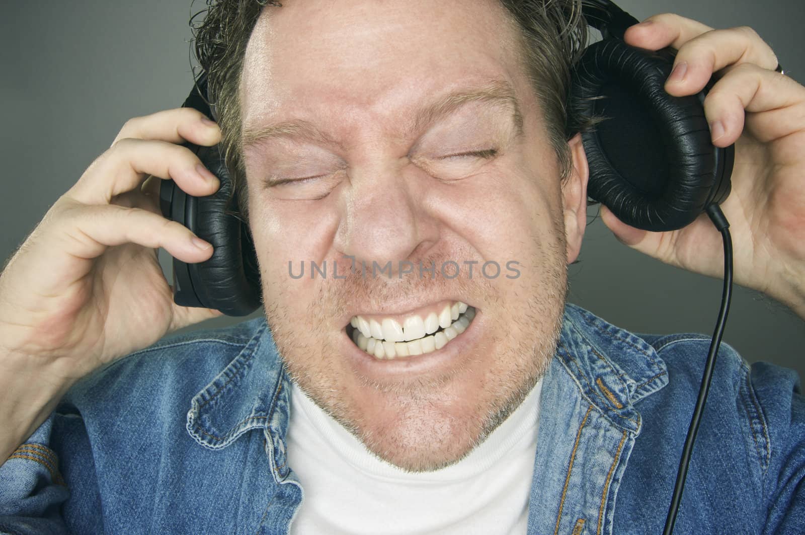 Shocked Man Desperately Trying To Take Off His Headphones.