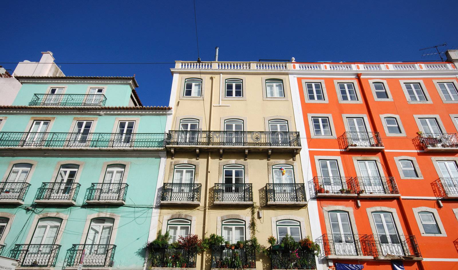 three facades of different colored houses in Lisbon
