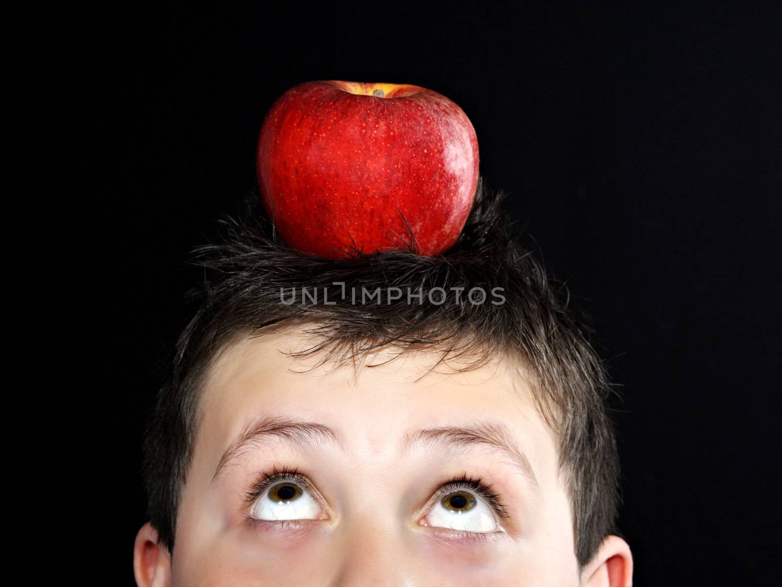 closeup portrait of a young teen boy with an apple on his head