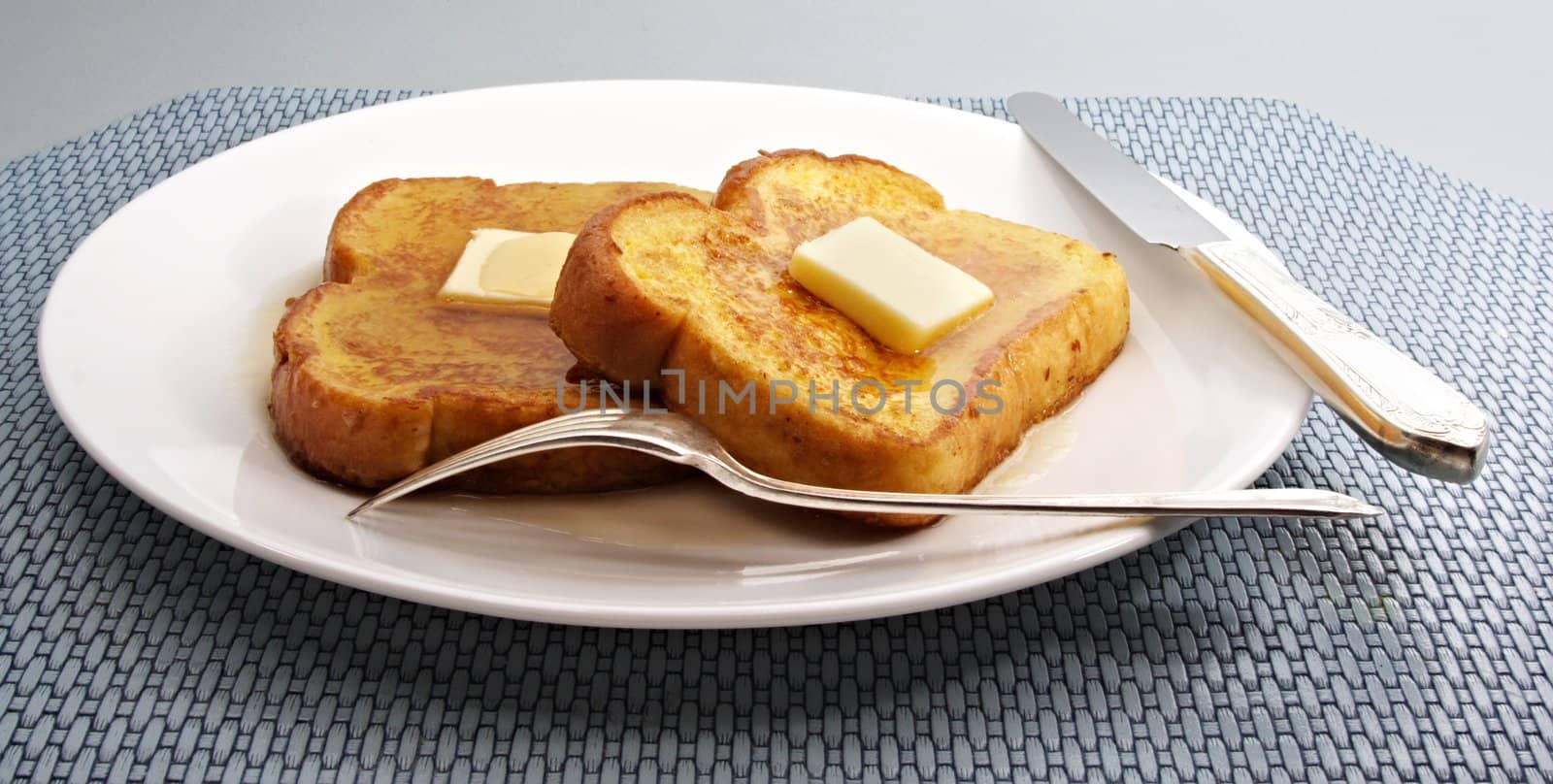 french toast with piece of butter on a white plate