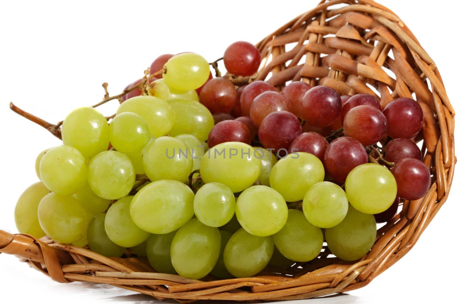 fresh green and red grape in a wicker basket, isolated on white