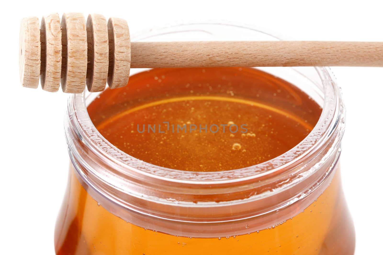 jar of honey with wood stick by lanalanglois