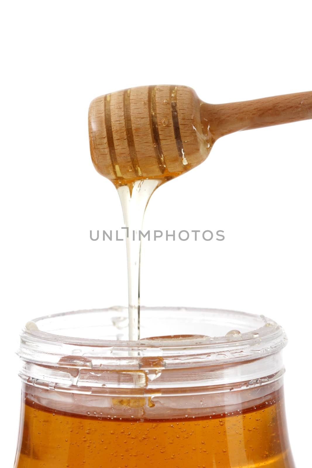jar of fresh honey with wood stick, white background