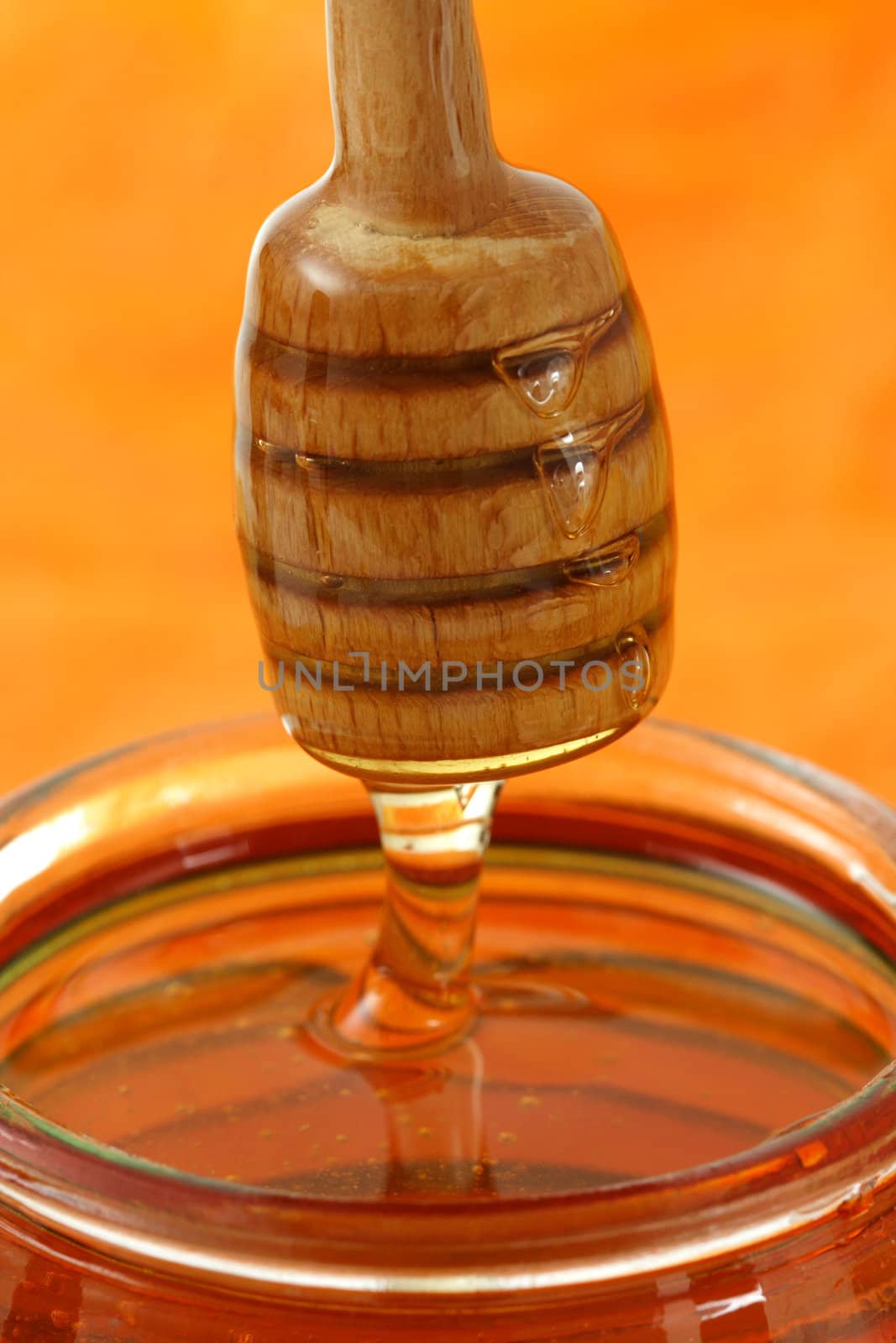 jar of honey with wood stick by lanalanglois