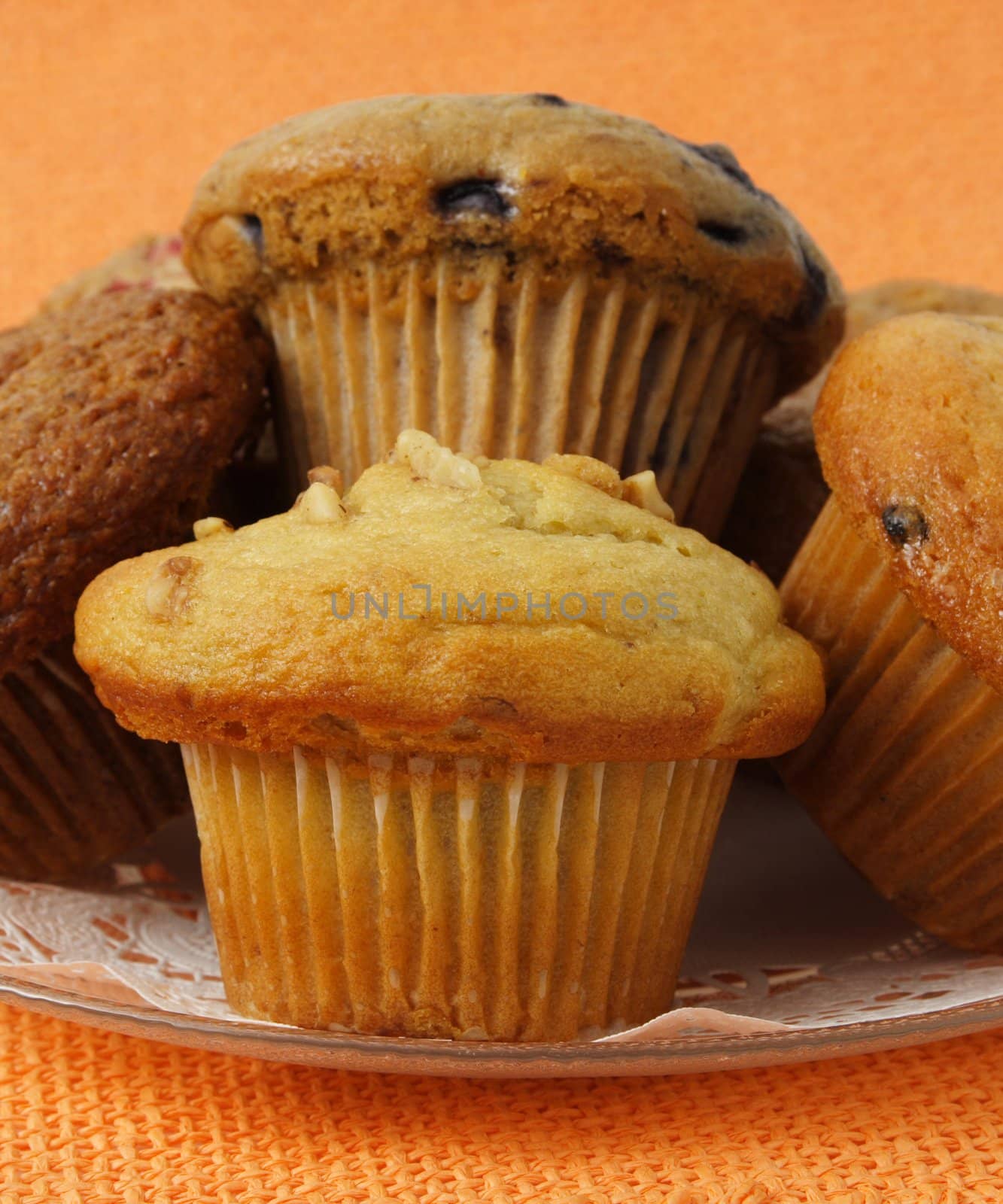 closeup on variety of muffins on a plate, orange tablecloth