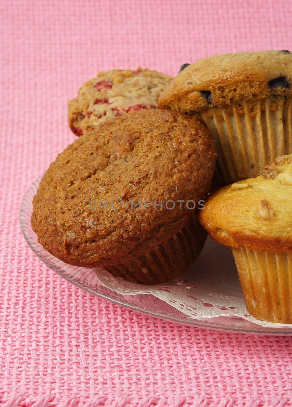 closeup on variety of muffins on a plate, pink tablecloth
