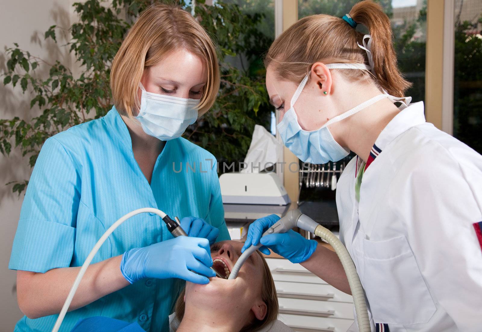 Female dentist drilling in the mouth of her patient