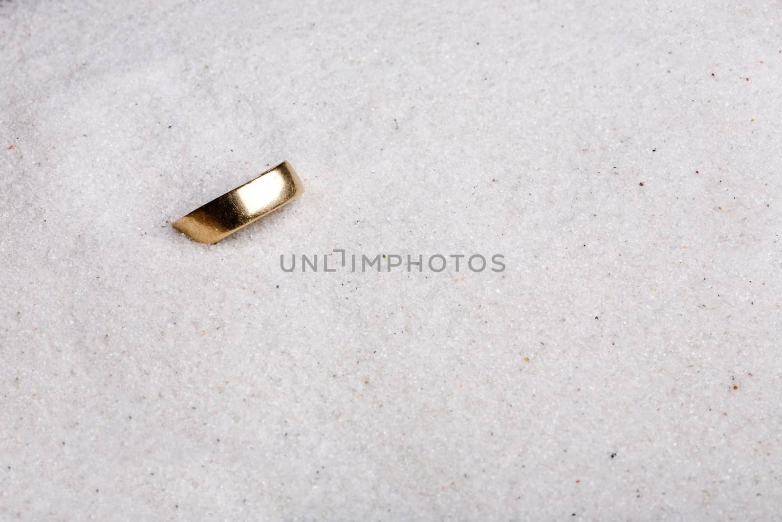 A lost ring hiding in soft white sand.