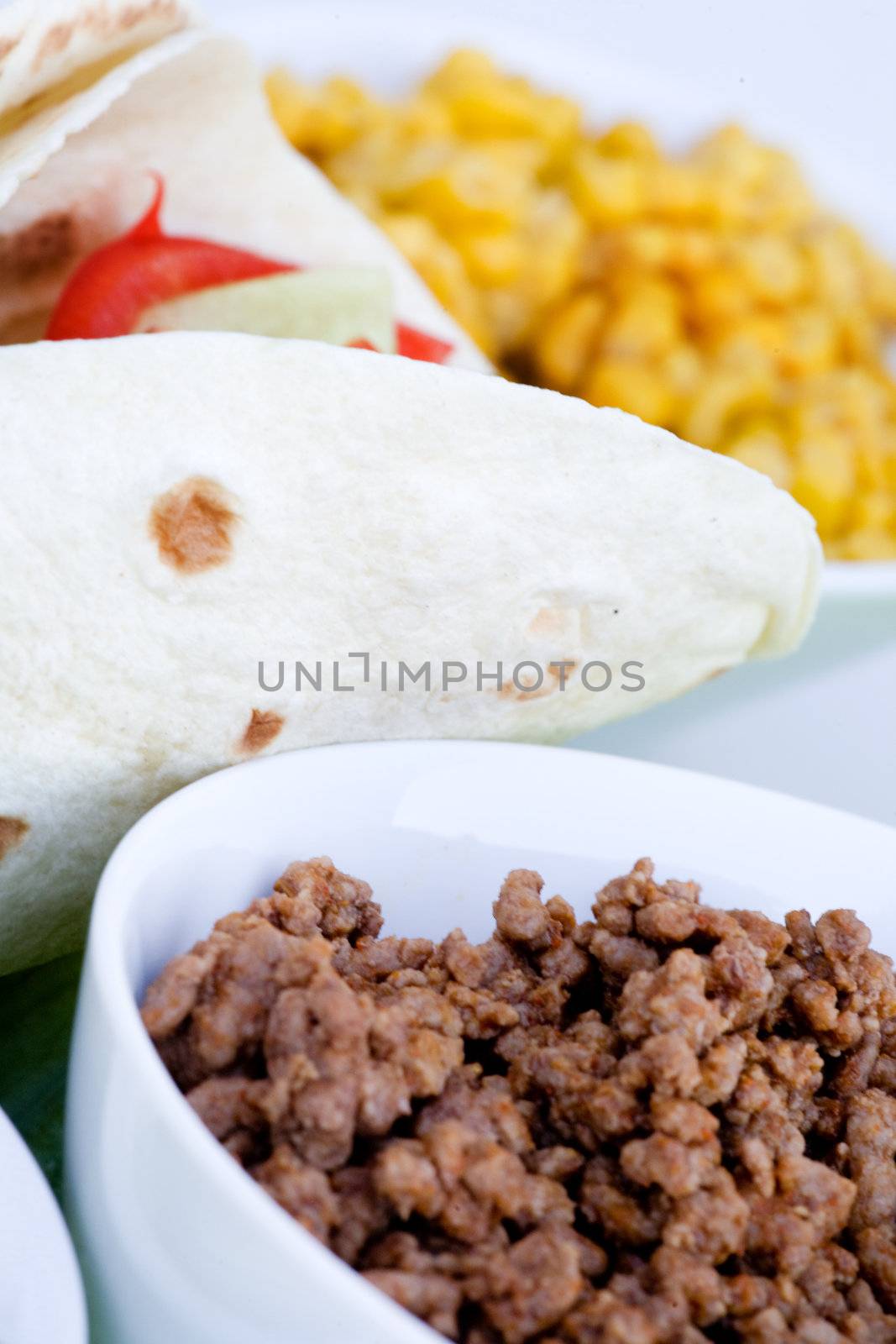 A macro of a prepared taco with ingredients in th background