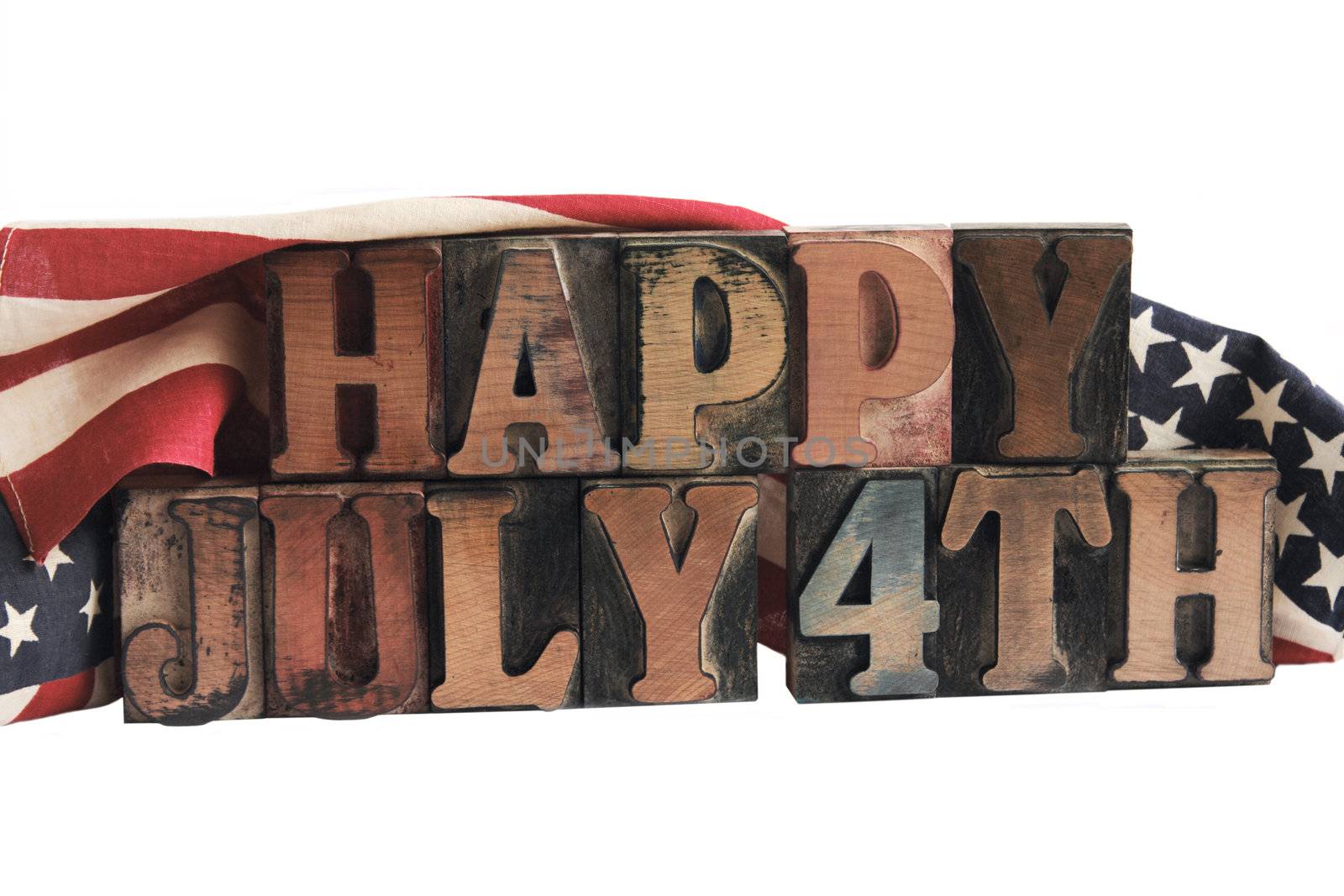 the phrase 'happy July 4th' in ink-stained letterpress type with flags draped behind
