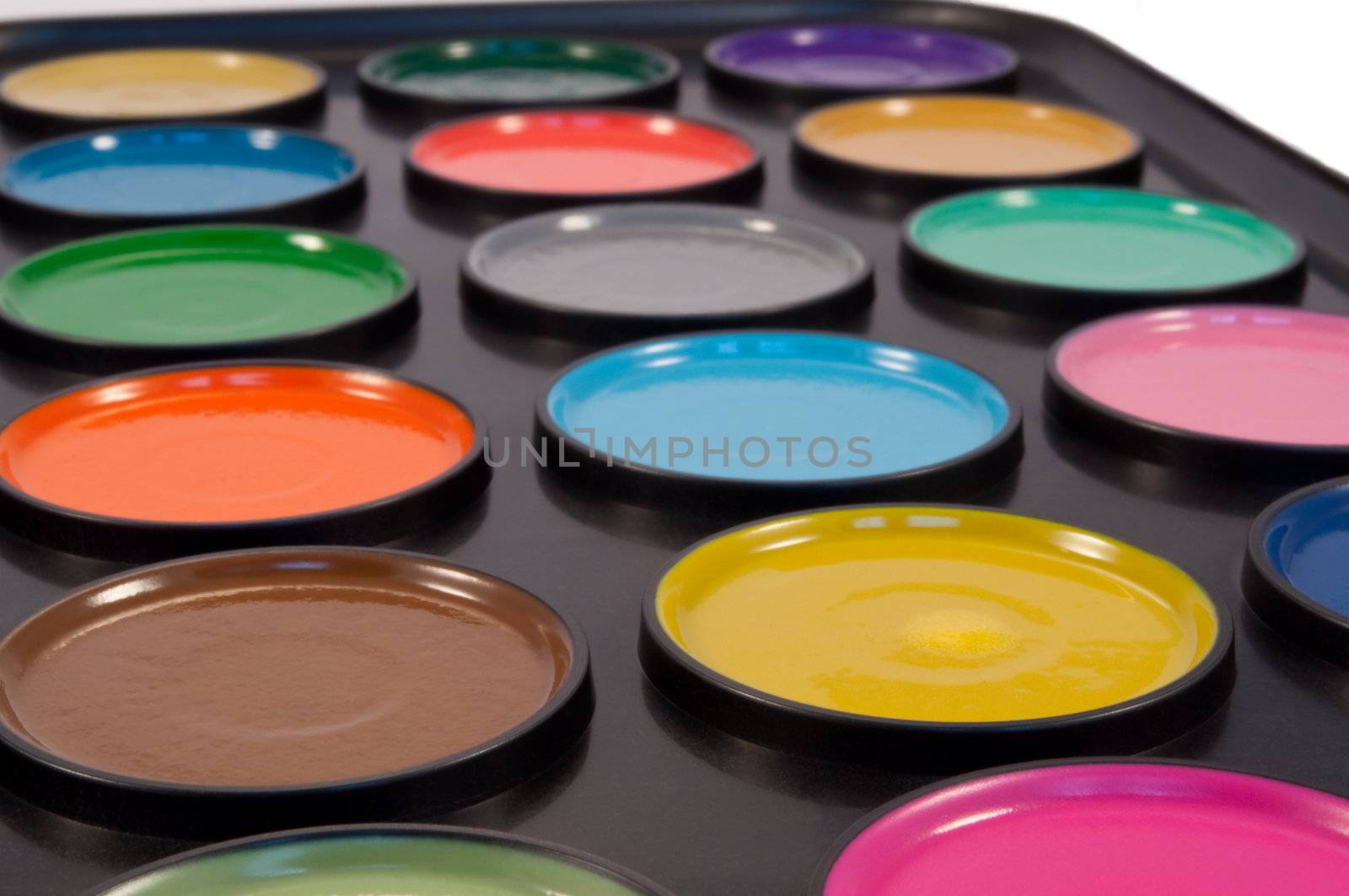 Close, low level capturing many watercolour paint discs within a child's painting set.