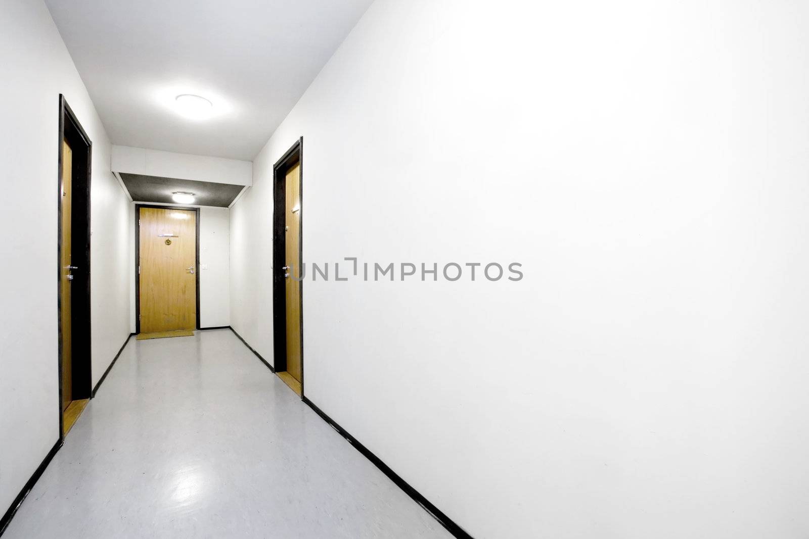 A sterile empty hallway with a single door open