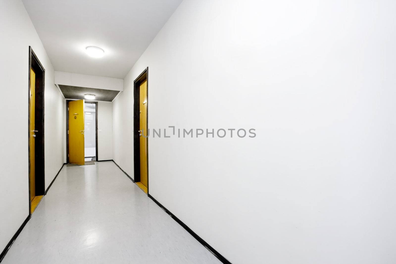 A sterile empty hallway with a single door open