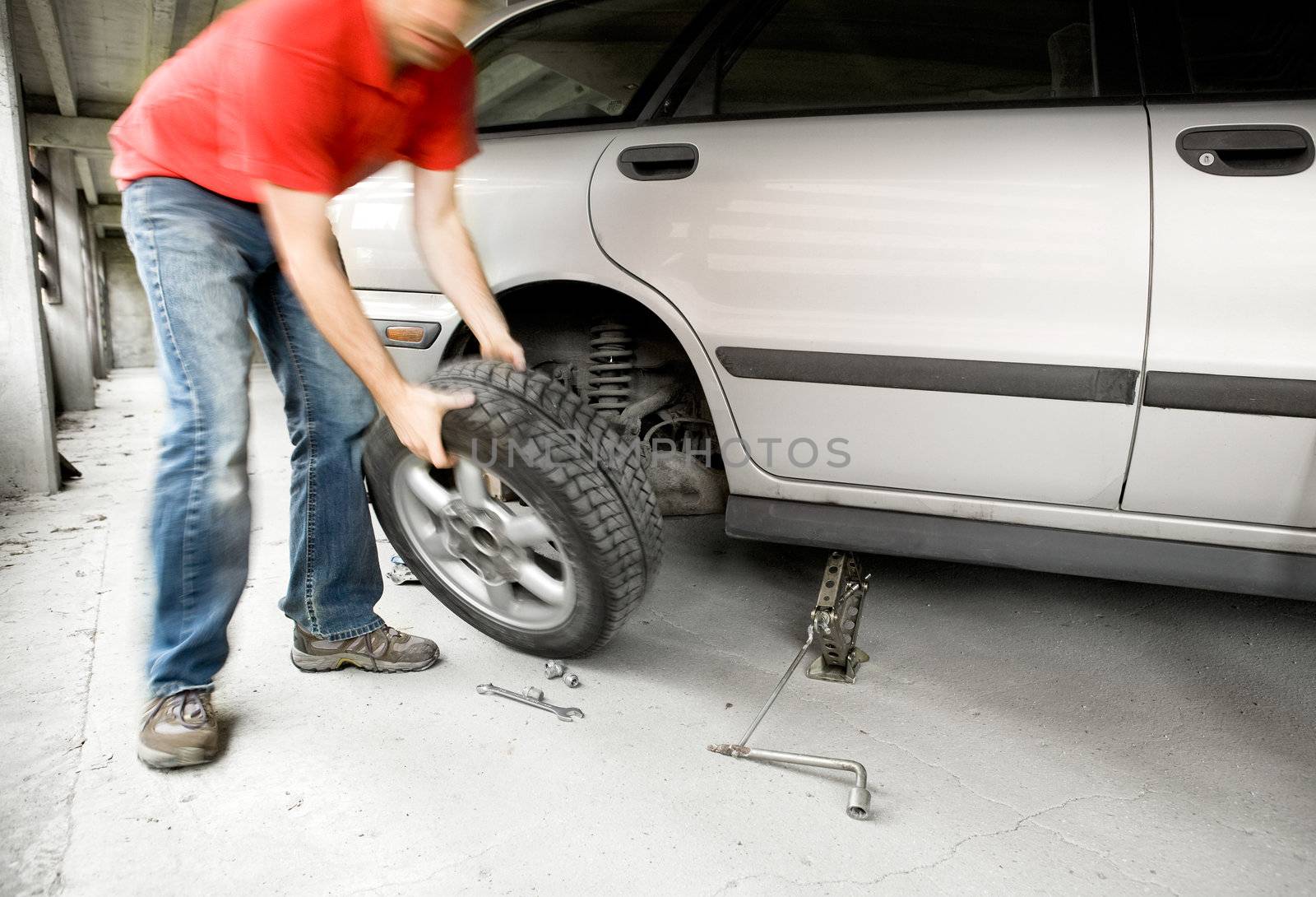 A male changing a tire on a car in a garage