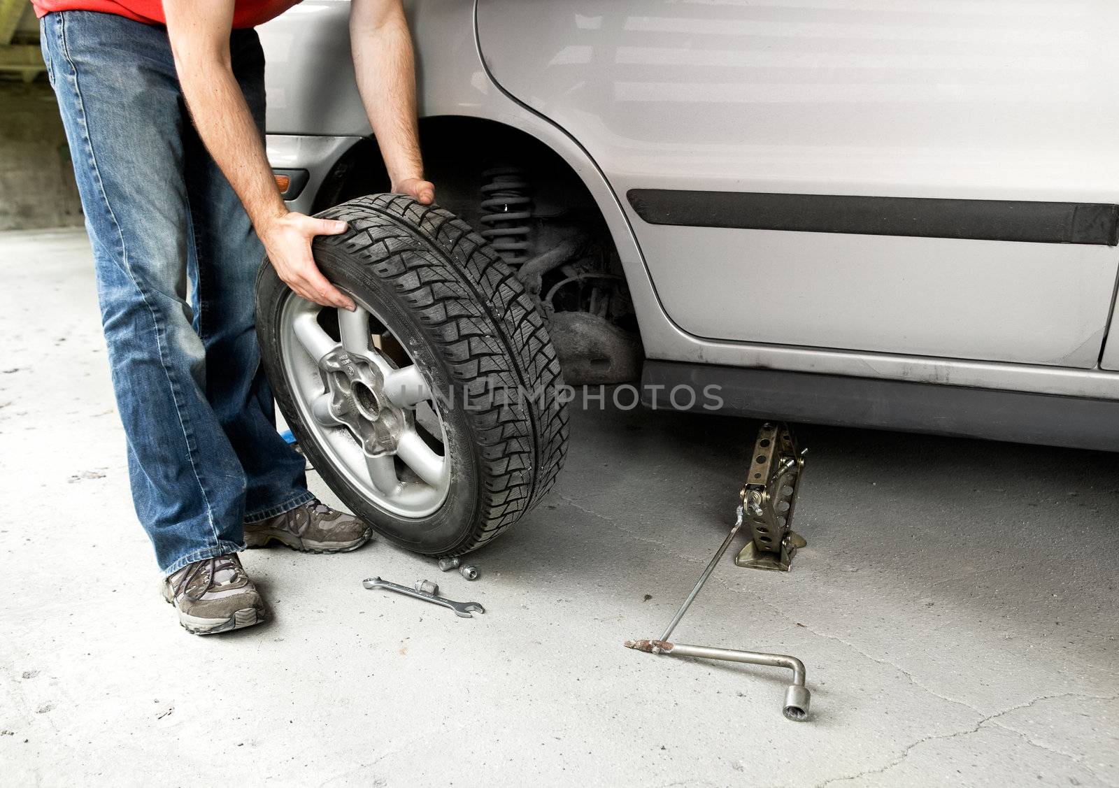 A male changing a tire on a car in a garage