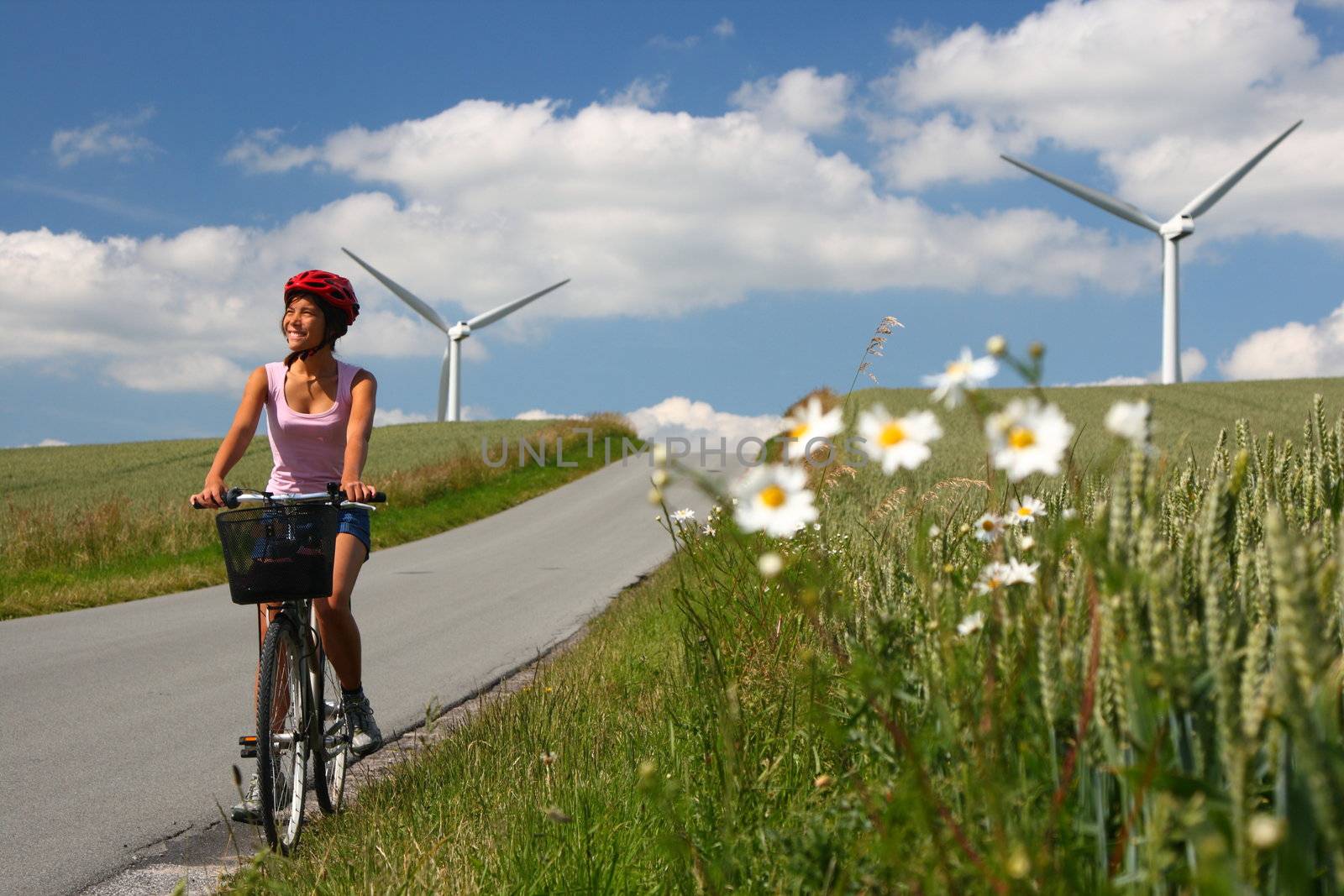 Woman relaxing and enjoying the sun on a bike trip in the countryside of Jutland, Denmark Windmill in the background.