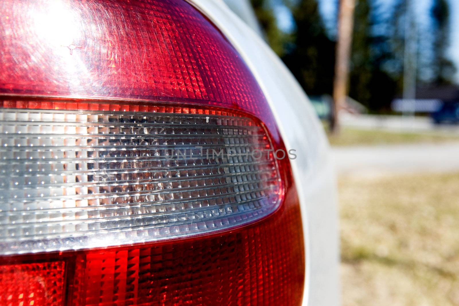 A red and white rear car light with sun reflection