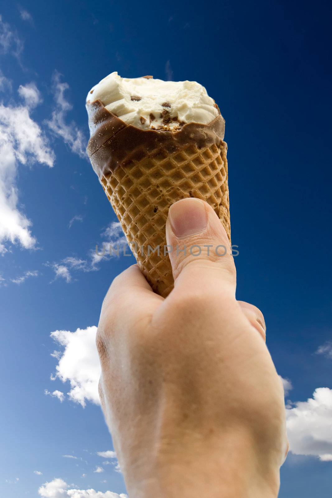 An ice cream cone with a bite isolated against a deep blue sky