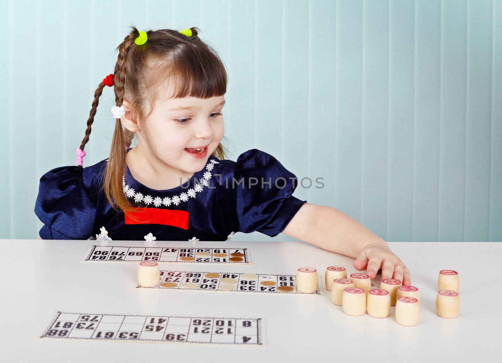 Little girl playing with lotto, sitting at the table