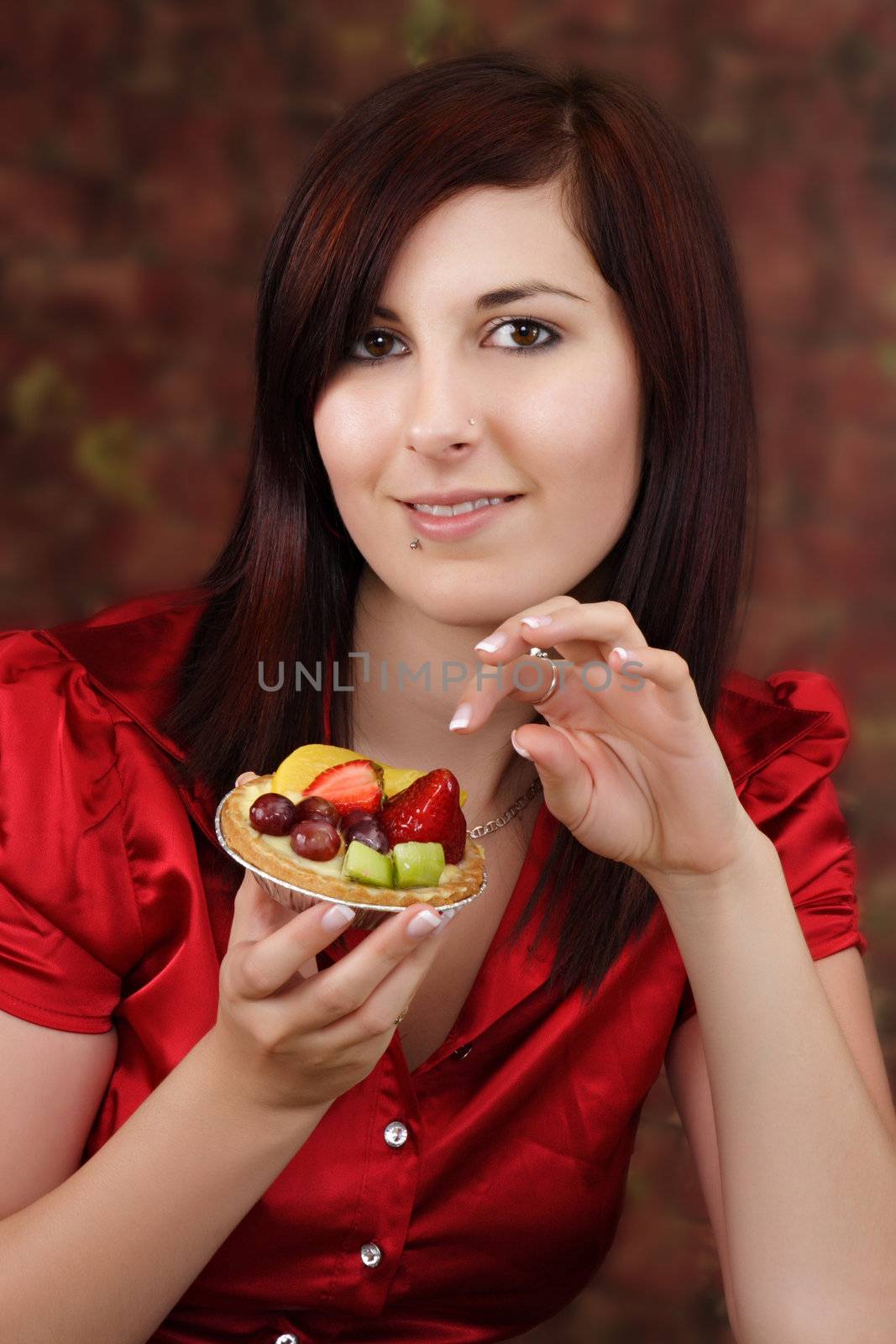 Young pretty woman holding a fruit tartlet