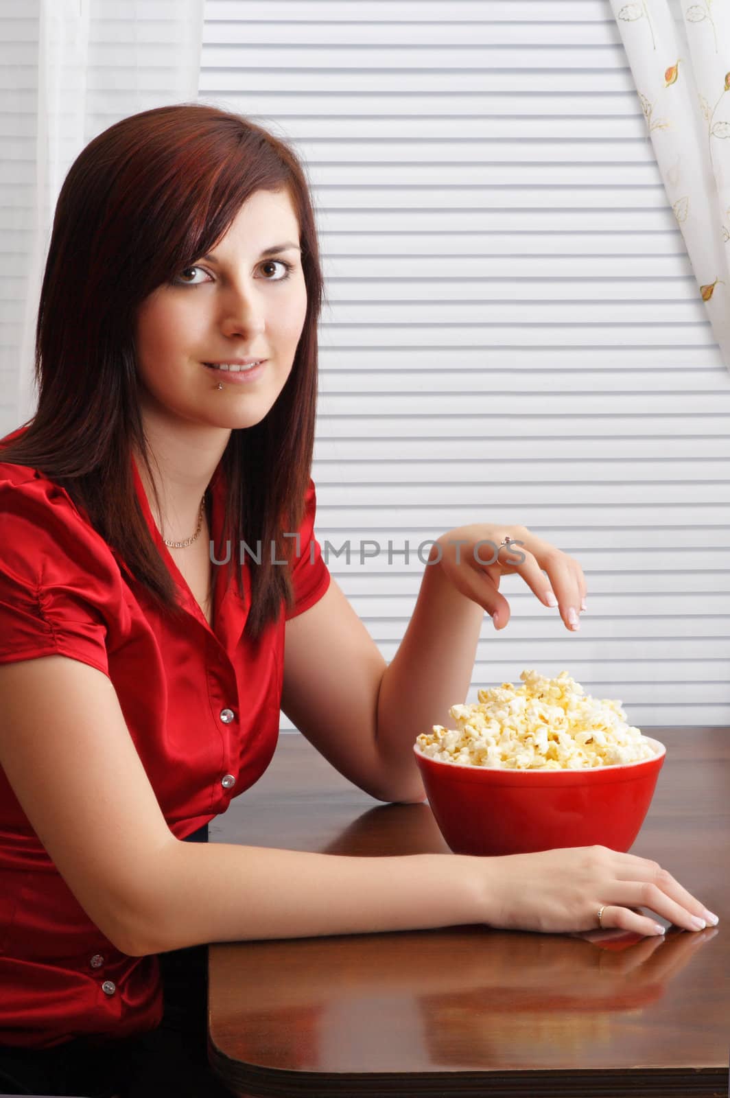 young woman at table, with popcorn in a red bowl