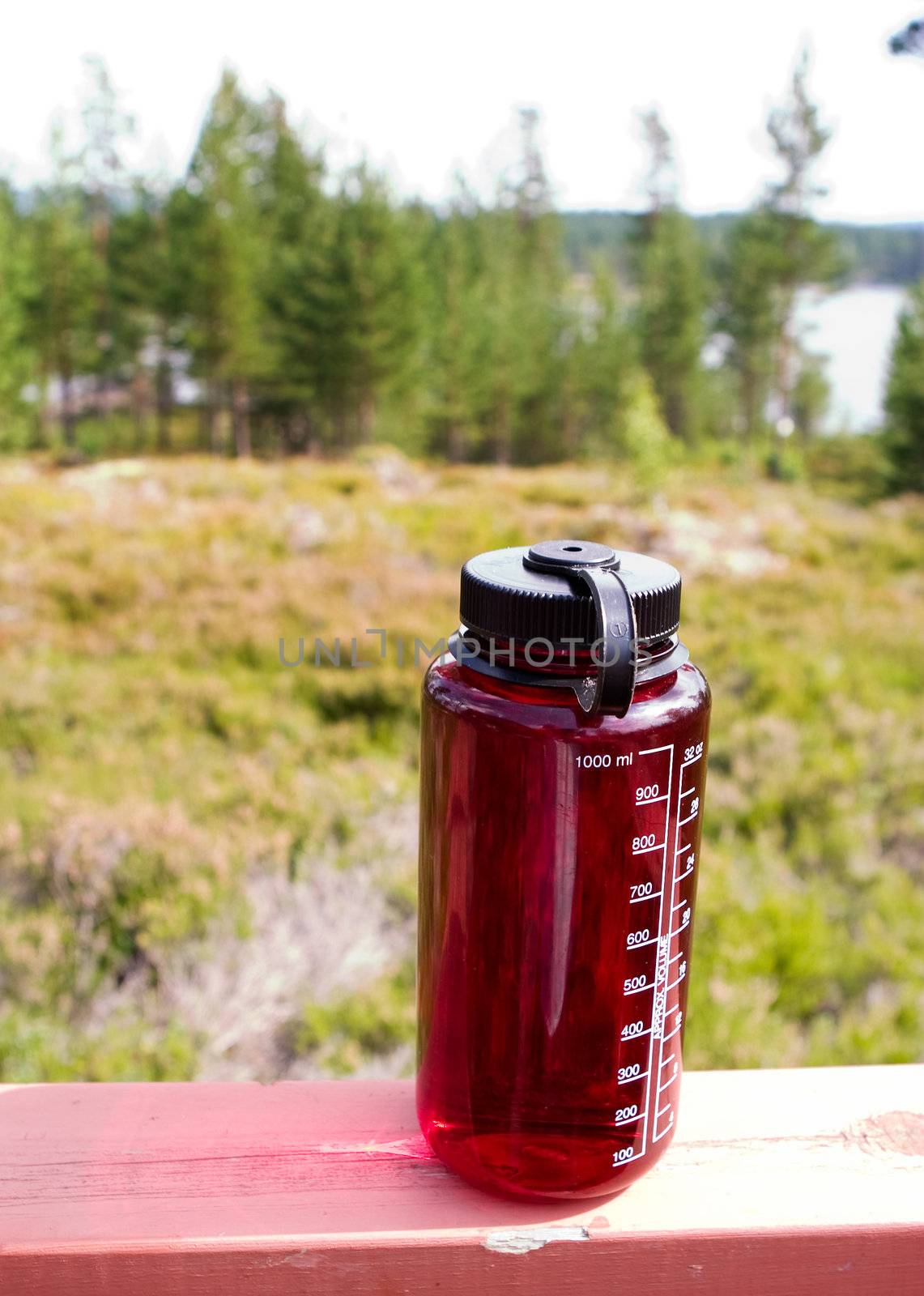 A red water bottle outdoors in nature