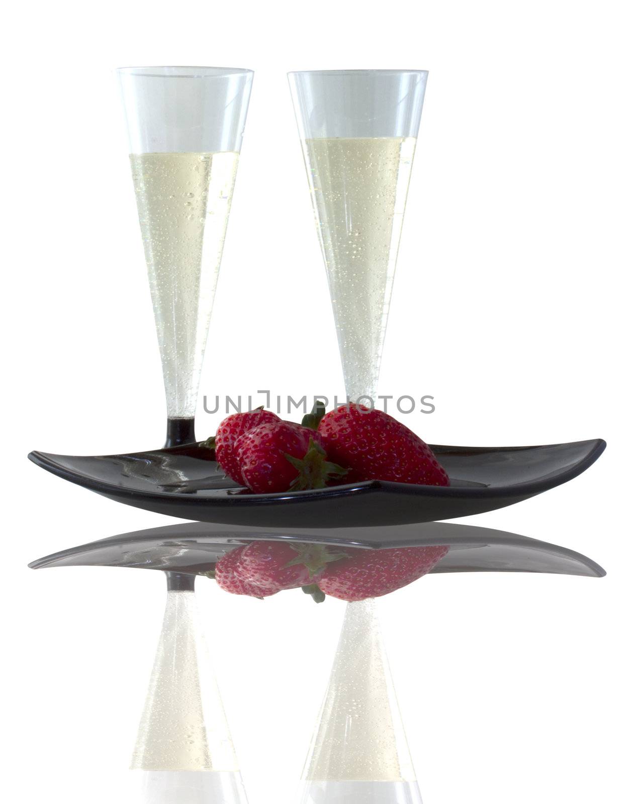 Two glasses of spumante and some strawberries on black plate