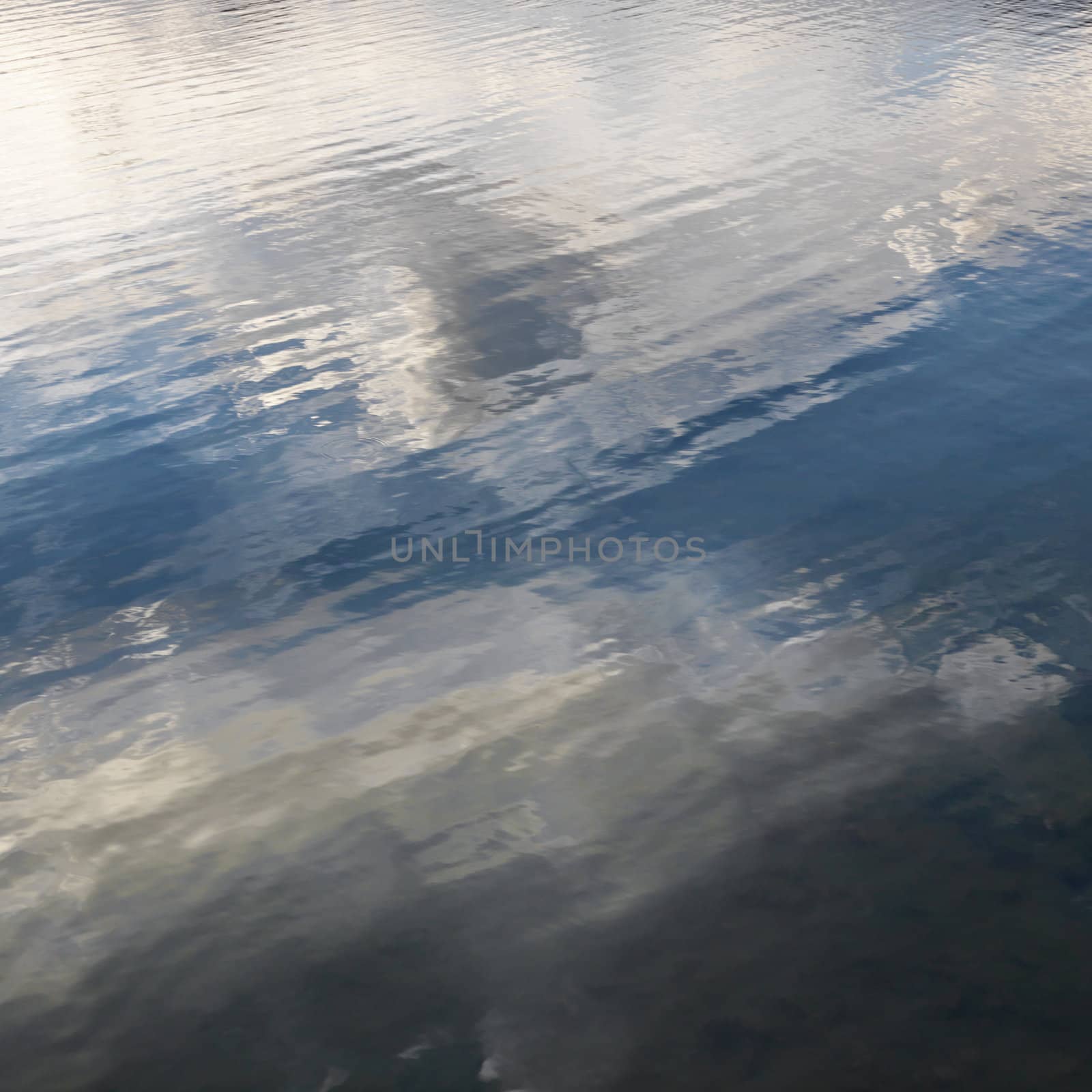 Reflections of cloud formations on rippling water.