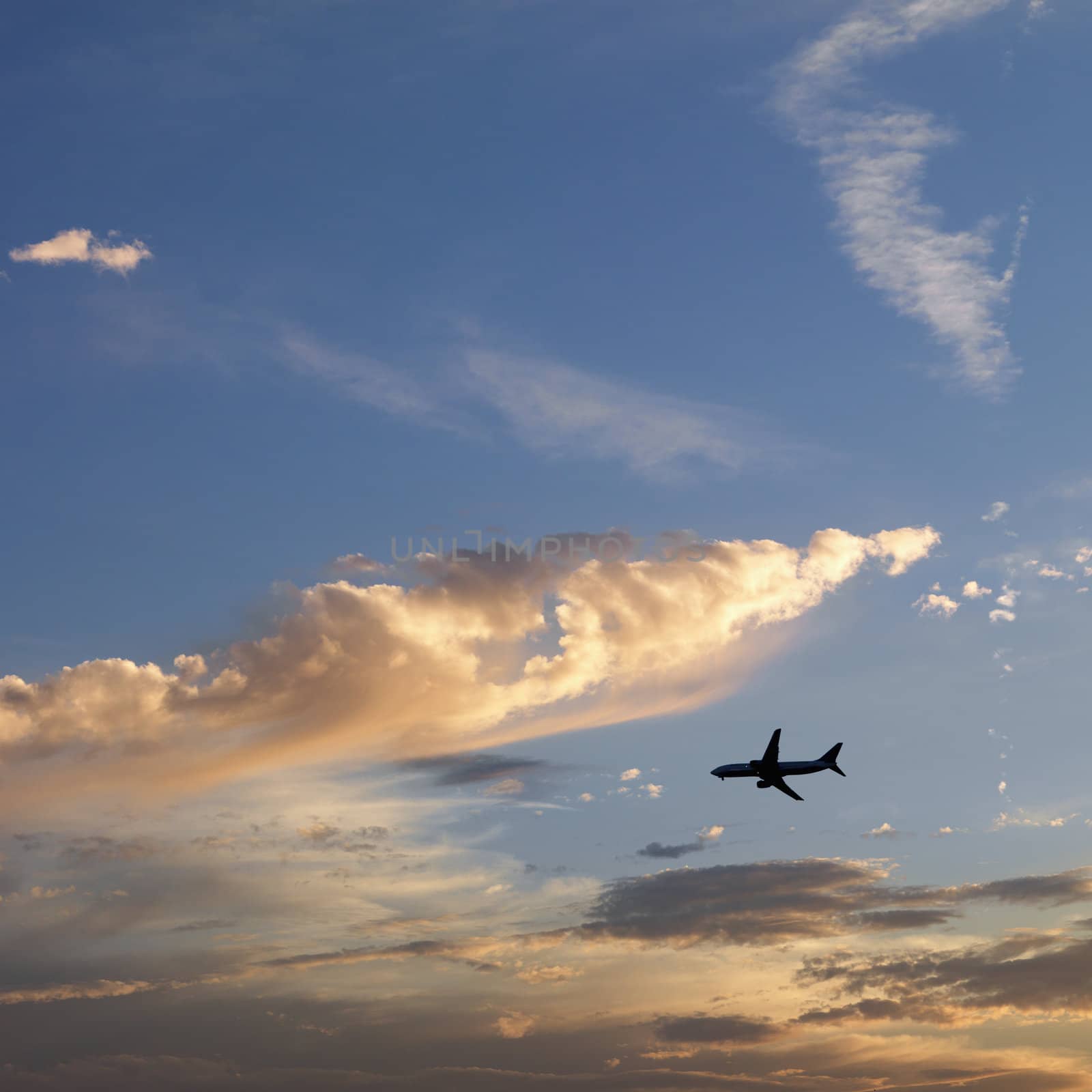 Airplane jetting across colored sky.