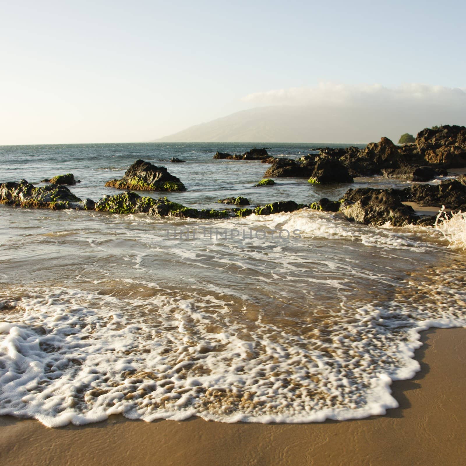 Landscape of waves lapping on rocky beach.