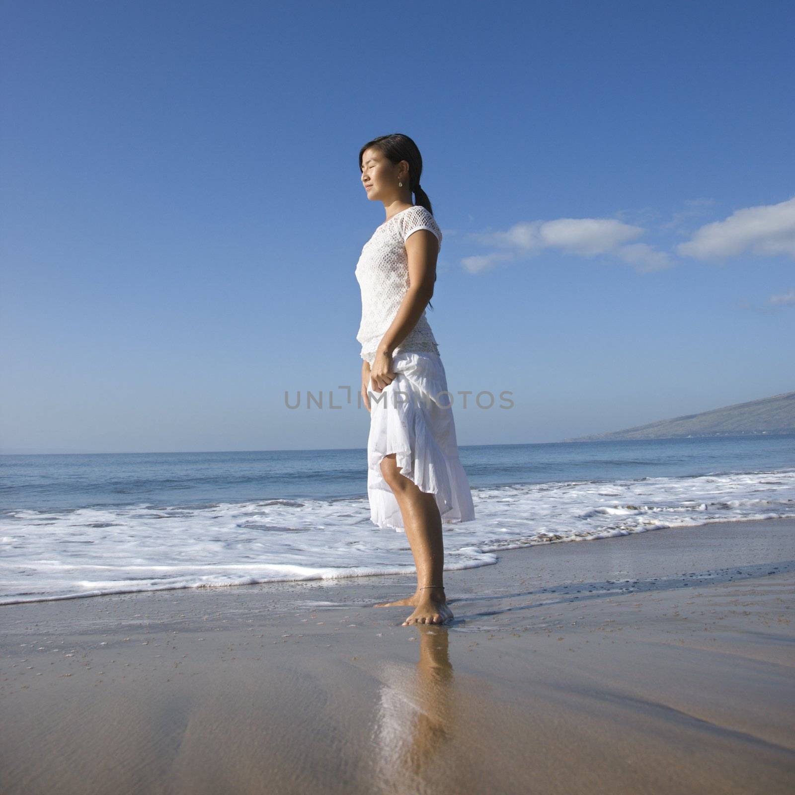 Young Asian female standing at shoreline.