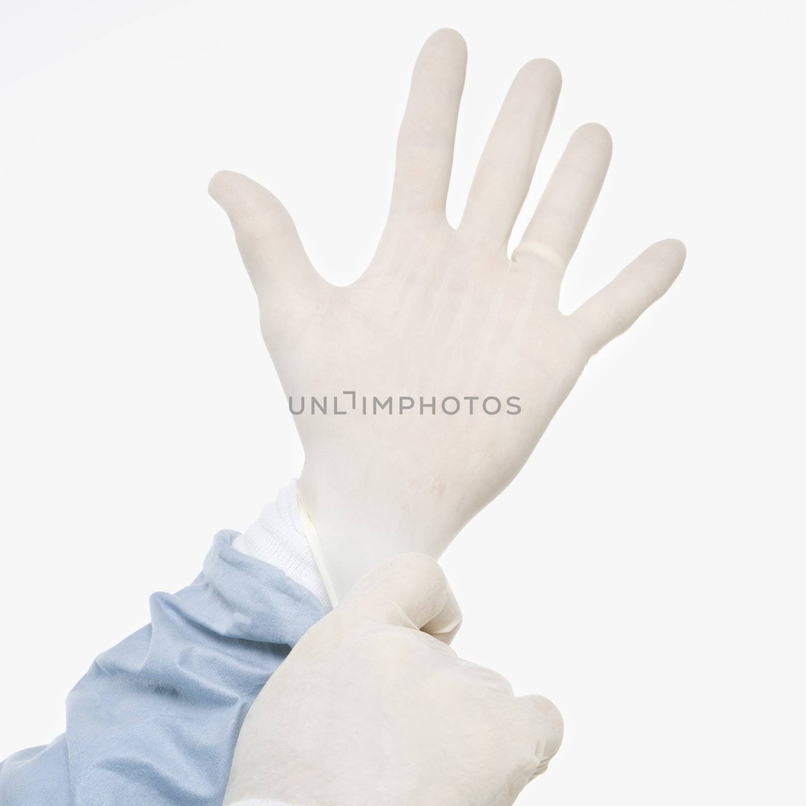 Mid-adult Caucasian male putting on latex medical gloves.